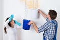 Woman With Worker Collecting Water From Ceiling In Bucket Royalty Free Stock Photo