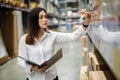 Woman worker holding clipboard and checking inventory in the warehouse store Royalty Free Stock Photo