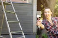 Woman worker holding paint brush in focus, painting wooden house exterior wall with paintbrush and wood protective color home Royalty Free Stock Photo