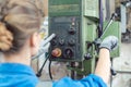 Woman worker in metal workshop operating power drill