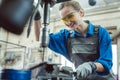 Woman worker in metal workshop using pedestal drill Royalty Free Stock Photo