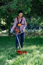 Woman worker mowing the grass in garden using string trimmer Royalty Free Stock Photo