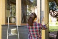 Woman worker painting wooden house exterior wall with paintbrush and wood protective color home improvement concept Royalty Free Stock Photo