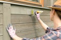 Woman worker painting wooden house exterior wall with paintbrush and wood protective color Royalty Free Stock Photo