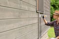 Woman worker painting wooden house exterior wall with paintbrush and wood protective color Royalty Free Stock Photo