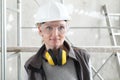 Woman worker portrait wearing helmet, safety glasses and hearing protection headphones, scaffolding interior construction site Royalty Free Stock Photo