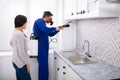 Woman And Worker Spraying Pesticide In Kitchen Royalty Free Stock Photo