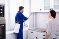 Woman And Worker Spraying Pesticide In Kitchen Royalty Free Stock Photo