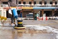 Woman worker using scrubber machine for cleaning polishing concrete floor.