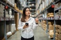 Woman worker using smartphone to checking inventory in warehouse store Royalty Free Stock Photo