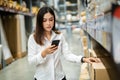 Woman worker using smartphone to checking inventory in warehouse store Royalty Free Stock Photo