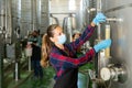 Woman vintner in mask checking wine process