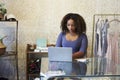 Woman working in clothes shop using laptop, front view