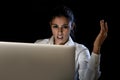 Woman working in darkness on laptop computer late at night surprised in shock and stress Royalty Free Stock Photo