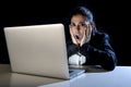 Woman working in darkness on laptop computer late at night surprised in shock and stress Royalty Free Stock Photo