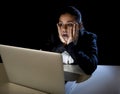 Woman working in darkness on laptop computer late at night surprised in shock and stress Royalty Free Stock Photo