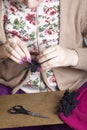 Woman working on a headdress. Sewing flower of cloth.