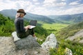 Woman working on her computer on the top of the mountain. Remote work