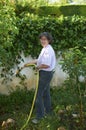 Woman working in her garden, watering and conditioning the land for planting Royalty Free Stock Photo