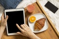 Woman working with her tablet and having breakfast