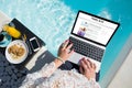 Woman working on her travel blog by the pool