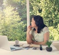 Woman working at home while looking out at bright daylight from