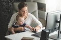 Woman working at home office and taking care of her baby son Royalty Free Stock Photo