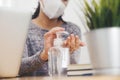 Woman working from  home  wearing protective mask. Cleaning her hands with sanitizer gel. Office worker on quarantine. Home Royalty Free Stock Photo