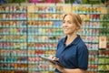 Woman Working Indoors In Garden Centre Using Digital Tablet In Front Of Colourful Display Of Seeds Royalty Free Stock Photo