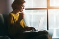 Woman working with laptop and coffee or tea at home quarantine