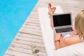 Woman working with laptop computer by the swimming pool