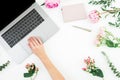 Woman working with laptop. Female hands with laptop and pink flowers on white background. Top view Royalty Free Stock Photo