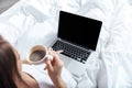 Woman working on laptop and having morning coffee in bed Royalty Free Stock Photo