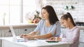 Woman working on laptop while her daughter doing homework Royalty Free Stock Photo