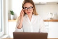 Woman working on laptop at home on kitchen. talking on phone. Blonde woman business. Woman trying to find a job