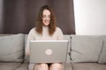 Woman working on laptop in home office while sitting on sofa. Young female student studying remotely on a computer Royalty Free Stock Photo