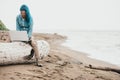 Woman working on laptop near the sea.