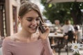 Woman working on laptop at office while talking on phone, backlit warm light. Portrait of young smiling business woman Royalty Free Stock Photo