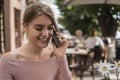 Woman working on laptop at office while talking on phone, backlit warm light. Portrait of young smiling business woman Royalty Free Stock Photo