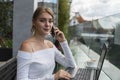 Woman working on laptop at office while talking on phone. Portrait of young smiling business woman calling her best Royalty Free Stock Photo