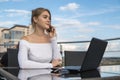 Woman working on laptop at office while talking on phone. Portrait of young smiling business woman calling her best Royalty Free Stock Photo