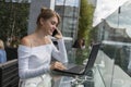 Woman working on laptop at office while talking on phone. Portrait of young smiling business woman calling her best Royalty Free Stock Photo