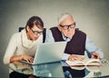 Woman working on laptop and older grandpa man reading from book Royalty Free Stock Photo