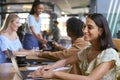 Woman Working On Laptop Sitting At Table In Busy Coffee Shop Royalty Free Stock Photo