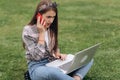 Woman working with laptop and smartphone while sitting in garden with green grass. Concept of people using mobile Royalty Free Stock Photo