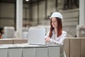 Woman working on laptop standing near stacked cargo
