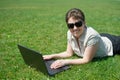 Woman working on laptop in summer outdoor, lie on your belly on green grass meadow, happy people, city park Royalty Free Stock Photo