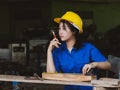 Woman working in mechanic uniform using measuring tools to cut wood sheets in factory