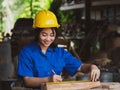 Woman working in mechanic uniform using measuring tools to cut wood sheets in factory