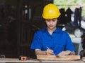 Woman working in mechanic uniform using measuring tools to cut wood sheets in factory